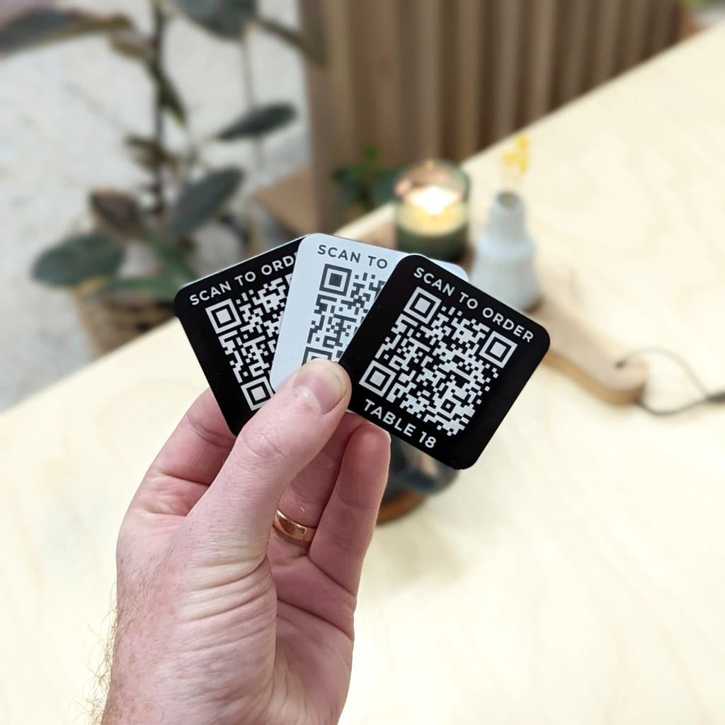 Hand holding table QR code cards that say scan to order